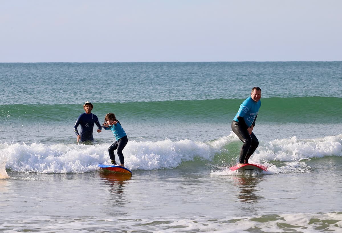 Un cours de surf en famille à Lacanau avec un père et sa fille sur la même vague
