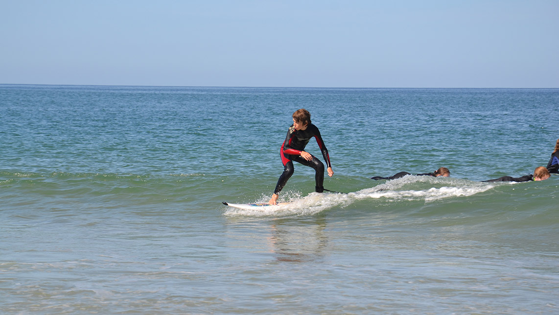 Jeune adolescent debout sur une vagues durant un cours de surf à Lacanau