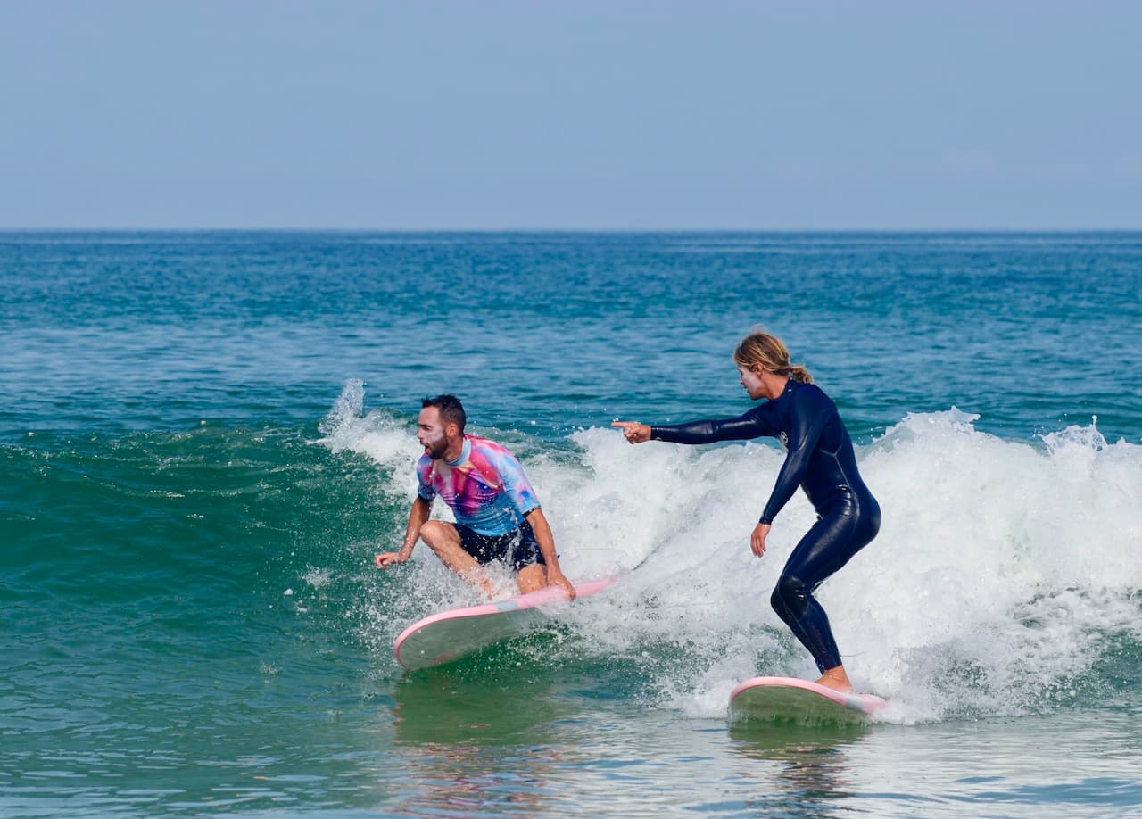 Un moniteur de surf donne des conseils en direct à son stagiaire sur la même vague