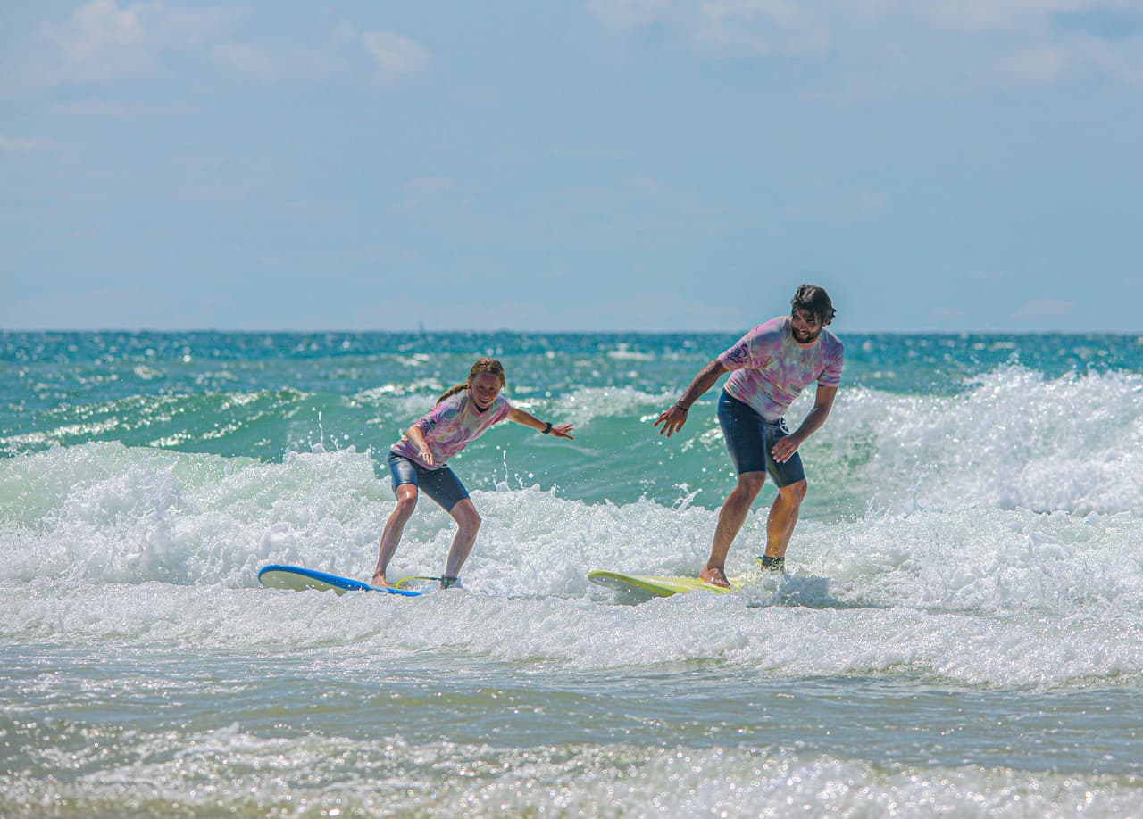 Papa et sa fille debout sur leurs planches pendant un cours de surf en famille à Lacanau