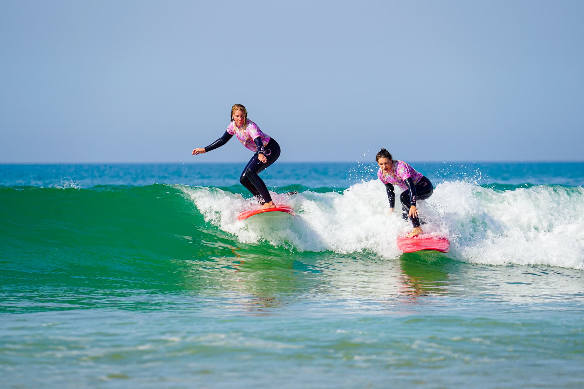 Deux surfeuses debout sur la même vague pendant un cours de surf à Lacanau