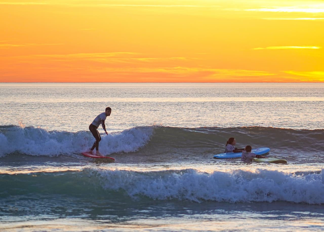 Un surfeur sur une vague à Lacanau avec un superbe soleil couchant en fond