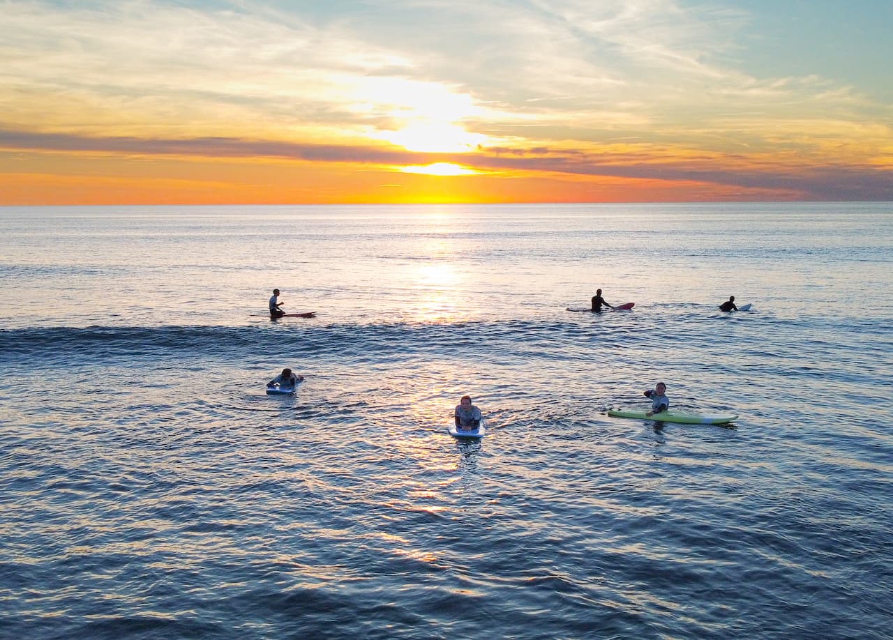Groupe de surfeurs attendant les vagues en admirant le coucher du soleil à Lacanau