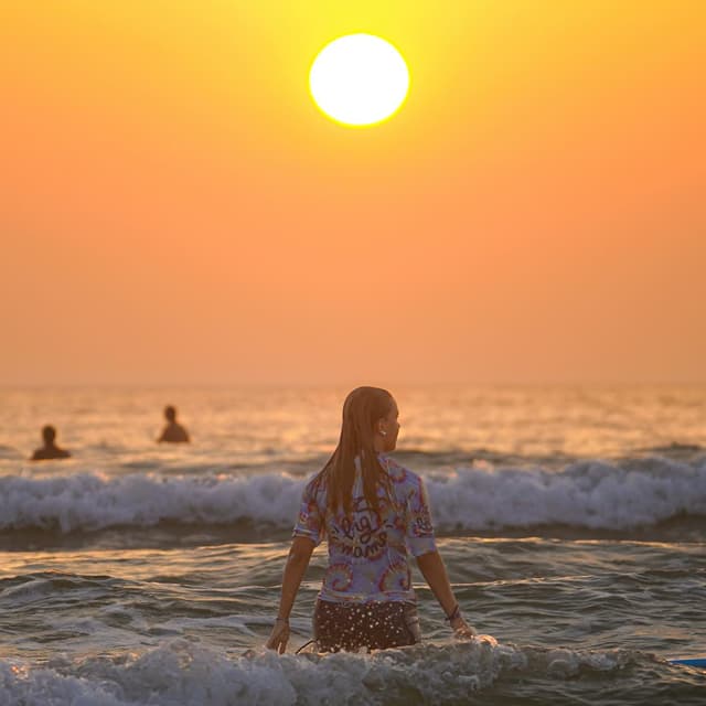 Jeune fille dans les vagues de Lacanau au coucher du soleil