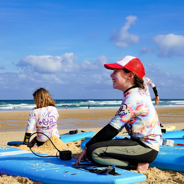 Jeune fille souriante sur la plage durant un stage de surf enfants à Lacanau