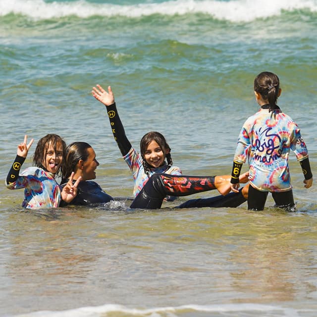 Groupe d'enfants jouant dans l'eau après un cours de surf chez Big Mama Surfschool